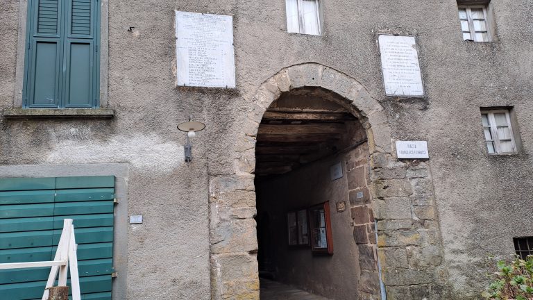 Volta di Piazza Ferrucci sormontata da due targhe, quella a sinistra ricorda la strage di Calamecca